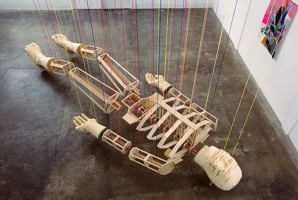A wooden sculpture of a person laying on the floor.