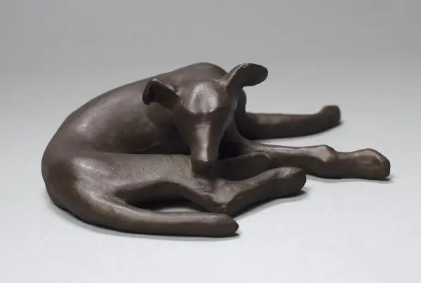 A bronze sculpture of a resting dog.
