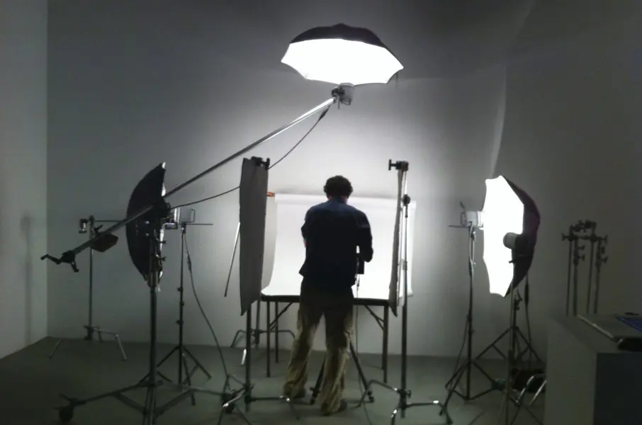 Photographer working in a studio with lights and backdrops.