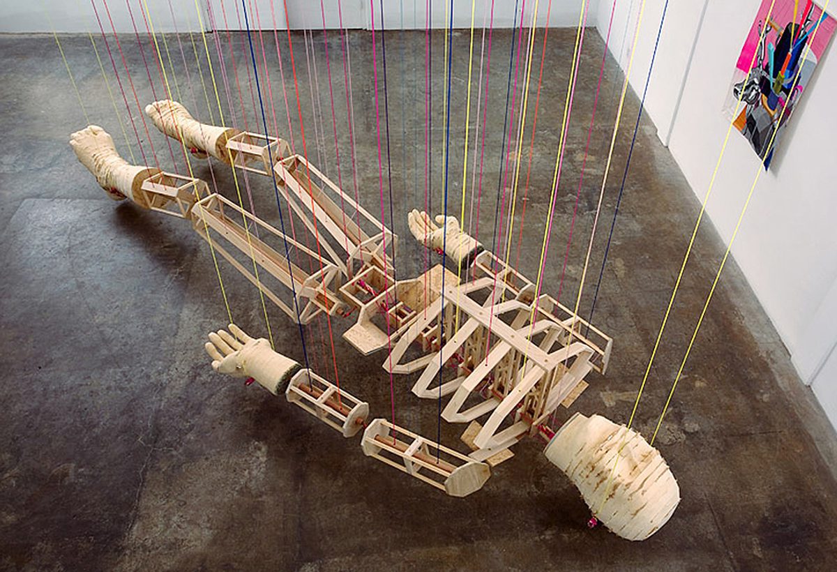 A wooden sculpture of a person laying on the floor.