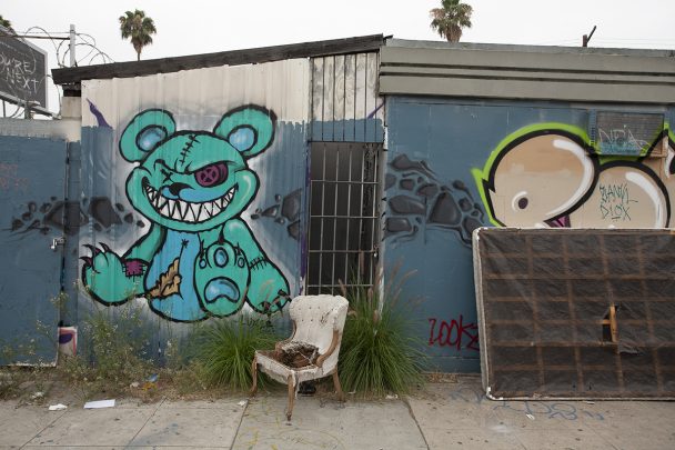 Graffiti of a teddy bear on a blue wall.