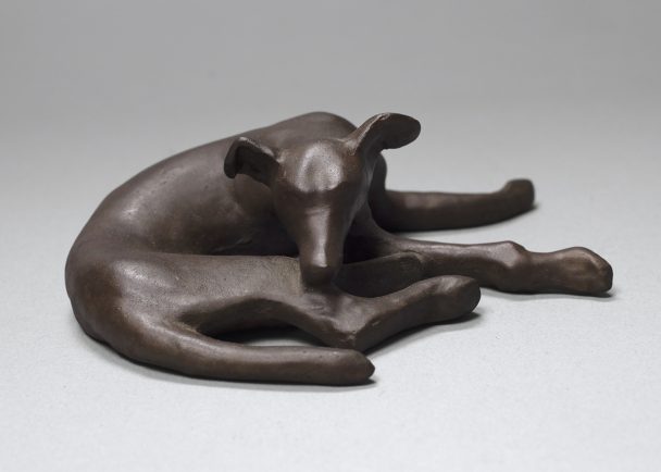 A bronze sculpture of a resting dog.