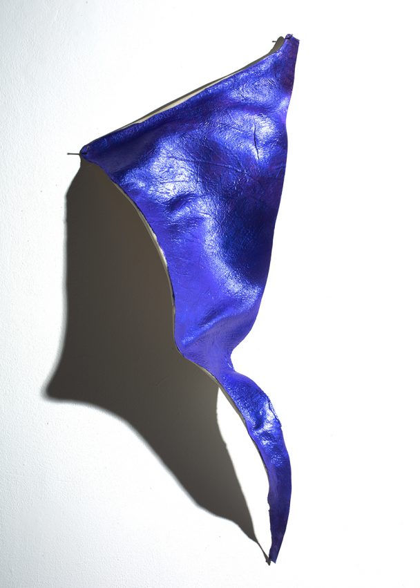 A blue leather-like material hangs on a white wall.