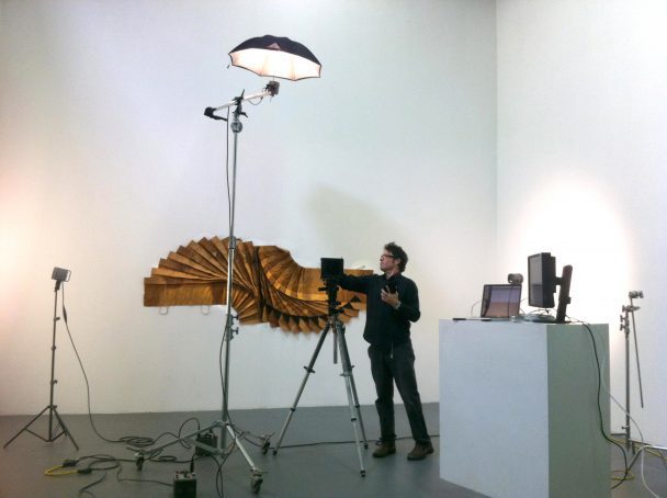 Man photographing art installation with tripod and lighting.