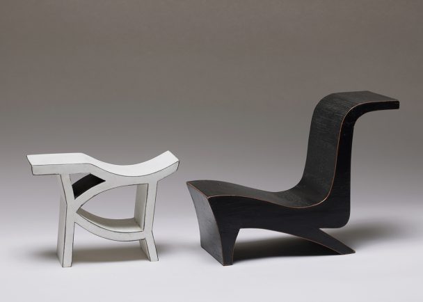 Black and white wooden sculptures of a chair and a stool.