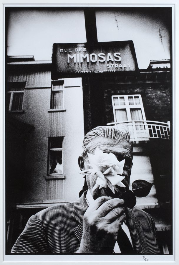 Black and white photo of a man smelling a flower.